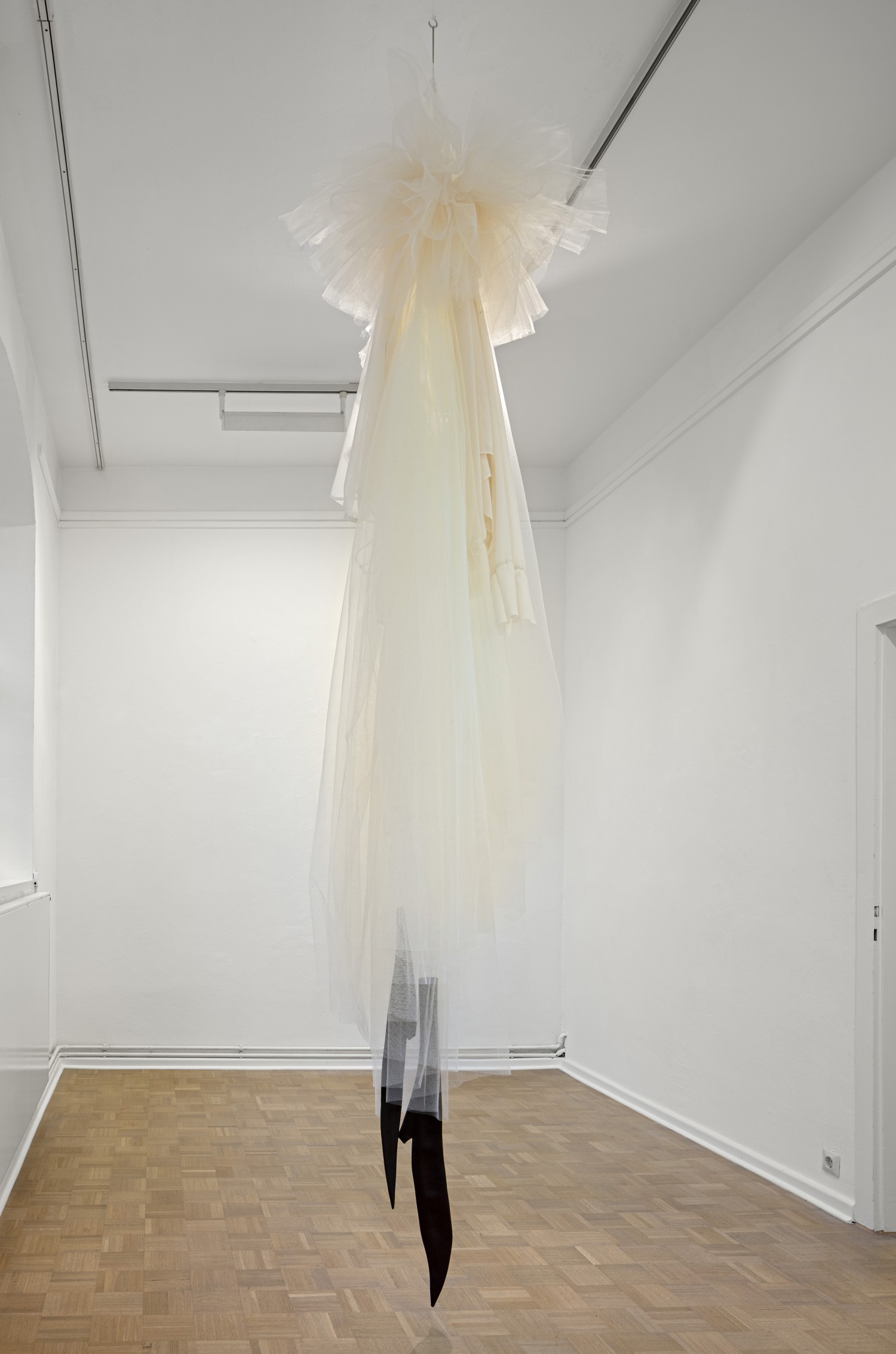 Die Arbeit "Loge" von Julie Béna besteht aus übergroßen, Raum einnehmenden Kleidungsstücken, die von der Decke herunterhängen und eine Irritation der Empfindung von Dimension und Raum auslösen.